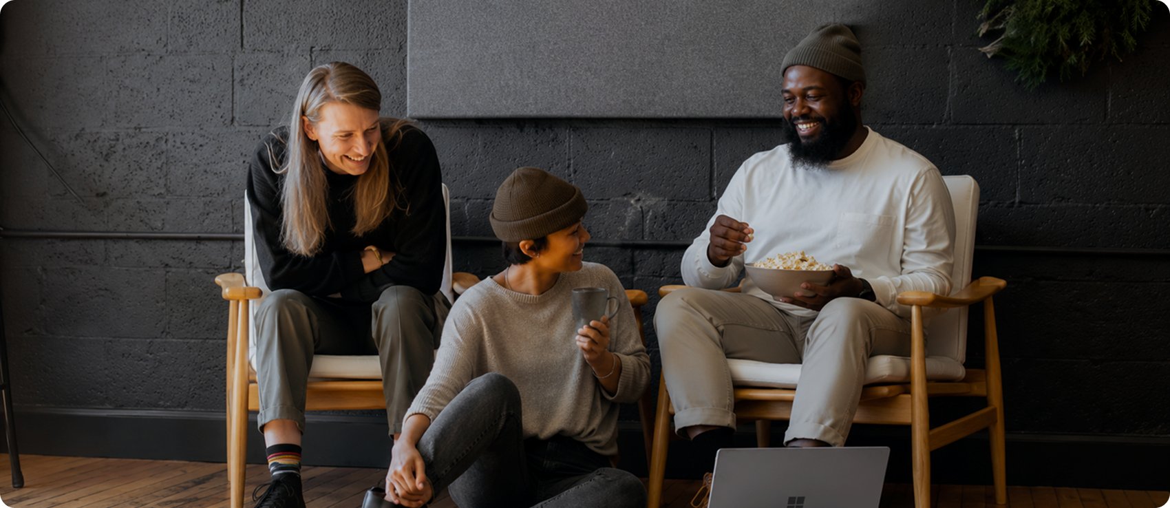Three colleagues laughing together around a laptop